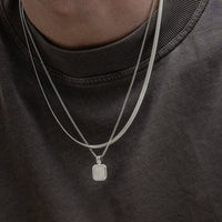 Lifestyle Aufnahme mit modernen Herren Halsketten aus 925 Sterling Silber getragen im Layering Look mit Snake Chain und minimalistischem Anhaenger fuer einen stilvollen maskulinen Look mit klarer moderner Aesthetik Sprezzi Fashion