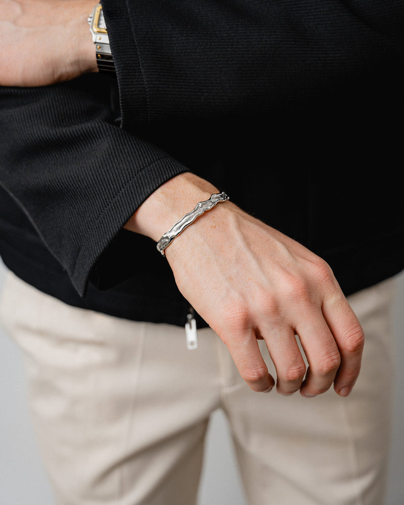 Am Handgelenk zeigt der Armreif seinen futuristischen Raw Charakter besonders kraftvoll da die meteoritenartige Struktur und die schmale offene Form modernen maennlichen Stil mit klarer technischer Praesenz verbinden Sprezzi Fashion