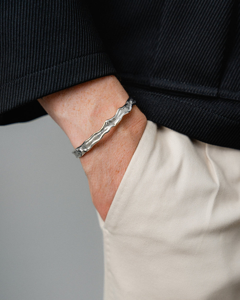 Die Modelaufnahme zeigt wie die meteoritenartige Struktur am Handgelenk kraftvolle Tiefe und modernen technischen Charakter entwickelt wodurch der Armreif stilvolle maennliche Praesenz erzeugt Sprezzi Fashion