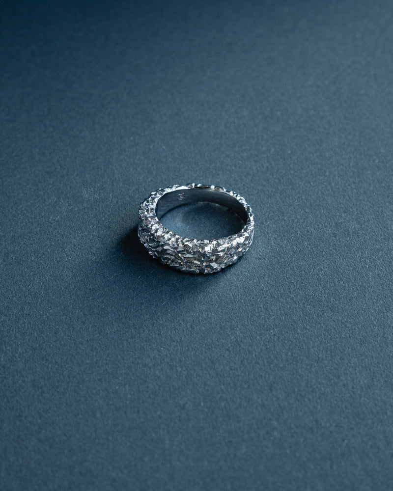 Der asymmetrische Bandring aus massivem 925 Silber zeigt eine meteoritenartige modellierte Oberflaeche die futuristische Tiefe und modernen Ausdruck erzeugt waehrend die stabile massive Verarbeitung klare maennliche Praesenz und zeitlose Eleganz betont Sprezzi Fashion