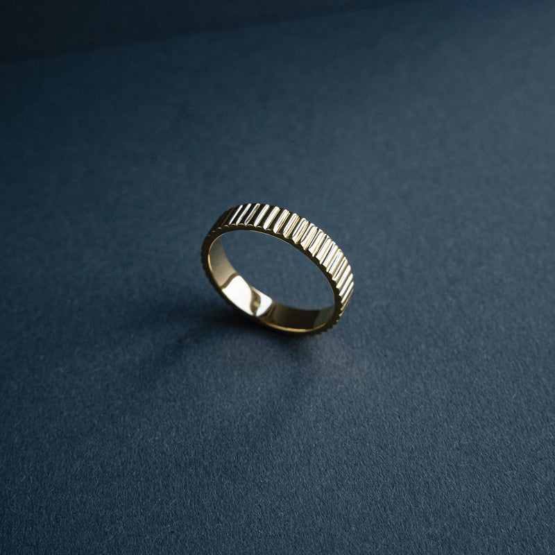 Der schmale Bandring Linear aus hochwertigem 18k Gold Vermeil vereint klare minimalistische Linien mit einer feinen geriffelten Struktur die modern und zugleich zeitlos wirkt und Maennern ein elegantes architektonisches Statement aus hochwertiger Verarbeitung bietet Sprezzi Fashion