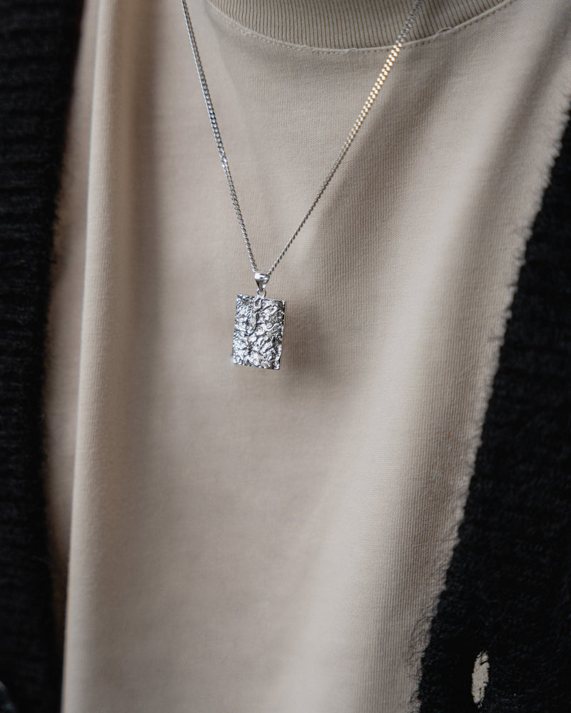 Die strukturierte Oberflaeche des rhodinierten Anhaengers zeigt meteoriteninspirierte Linien die futuristische Tiefe und modernen maskulinen Ausdruck erzeugen Sprezzi Fashion