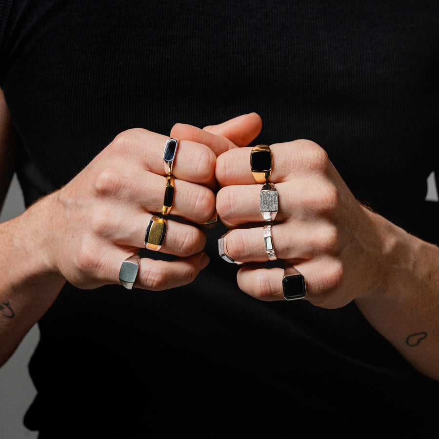 Hände mit mehreren Herrenringen in Silber und Gold zeigen bewusstes Ring Layering mit unterschiedlichen Breiten markanten Formen und modern maskuliner Wirkung Sprezzi Fashion