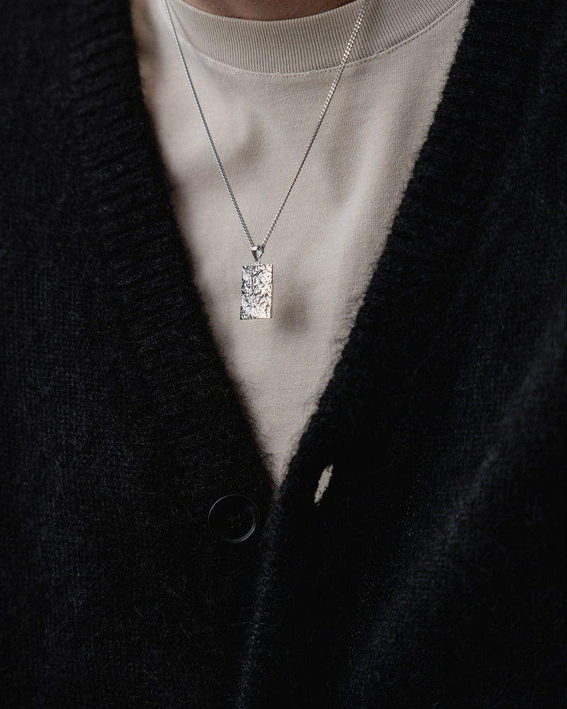 Getragen wirkt der eckige rhodinierte Anhaenger markant und zeigt meteoritenartige Struktur die modernen technischen Stil und maennliche Praesenz erzeugt Sprezzi Fashion