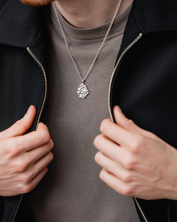 Getragen wirkt der ovale rhodinierte Anhaenger markant und die meteoritenartige modellierte Struktur erzeugt modernen technischen Stil mit maskuliner Ausstrahlung Sprezzi Fashion