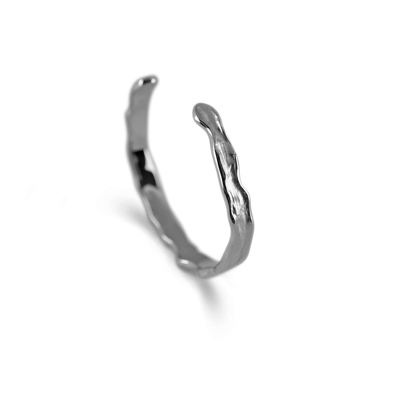 Die Seitenansicht zeigt die schmale offene Silhouette des meteoriteninspirierten Armreifs dessen markante Raw Struktur moderne Tiefe und maennlichen technischen Charakter vermittelt waehrend das massive Silber hochwertig wirkt Sprezzi Fashion