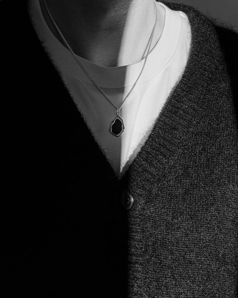 Ein Mann traegt die 925 Sterling Silber Halskette mit schwarzem Onyx Crash Anhaenger das markante Design spiegelt Charakter und Eleganz der polierte Silberglanz betont modernen Stil Sprezzi Fashion