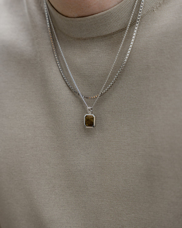 Ein Mann traegt zwei Halsketten aus 925 Sterling Silber eine mit Larvikit Stein und eine mit markanter Boxes XL Struktur das Zusammenspiel aus Glanz und Form zeigt moderne Eleganz Sprezzi Fashion