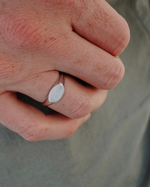 Makroaufnahme des minimalistischen Herrenrings offenbart die präzise verarbeitete Raw Struktur und betont die moderne Balance aus feiner Textur und zeitloser Silberoptik Sprezzi Fashion