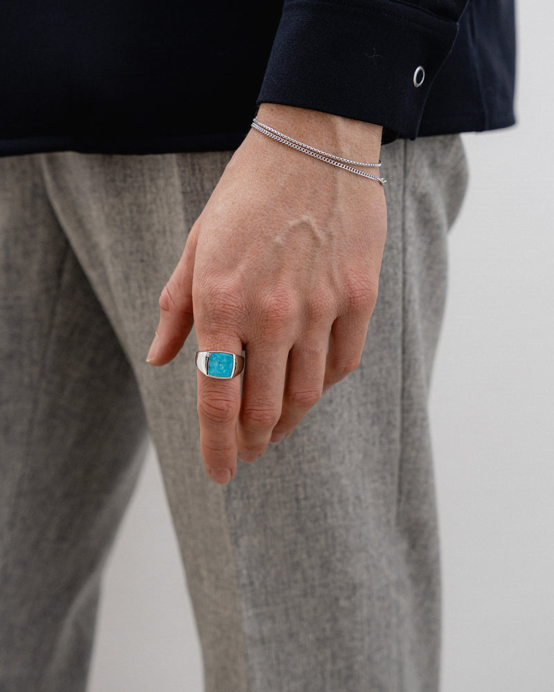 Ein Mann traegt das Box Thin Armband aus 925 Silber im Mittelpunkt des Looks kombiniert mit einem Tuerkis Siegelring und Small Curb Armband gefertigt in feiner Handarbeit von Sprezzi Fashion