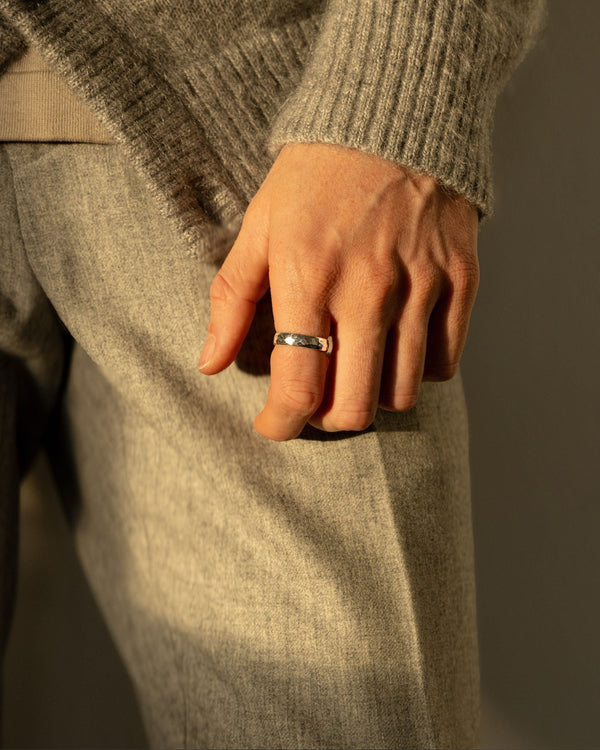 Ein Mann traegt den gehaemmerten Silberring aus 925 Sterling das Licht betont die strukturierte Oberflaeche und den klaren Glanz fuer modernen maskulinen Stil Sprezzi Fashion