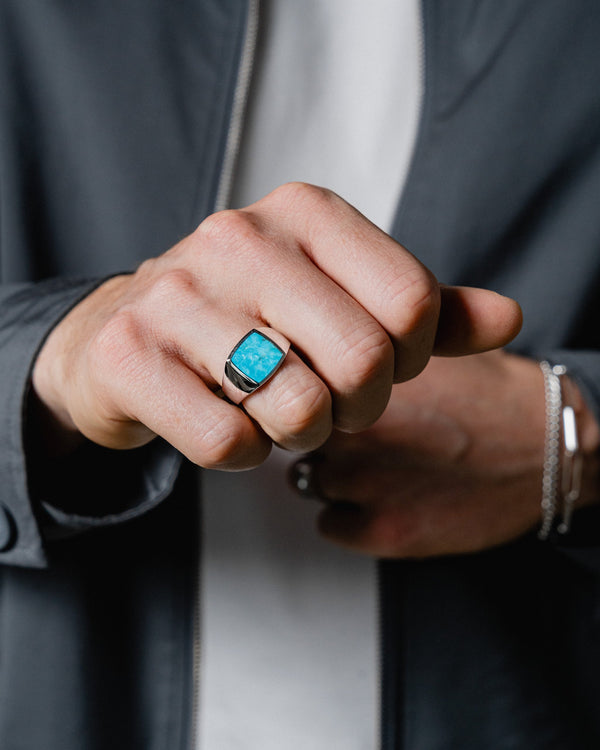 Ein Mann traegt den Siegelring mit Tuerkis Stein aus 925 Silber der leuchtende Stein reflektiert das Licht intensiv und betont maskulinen Stil und Eleganz Sprezzi Fashion