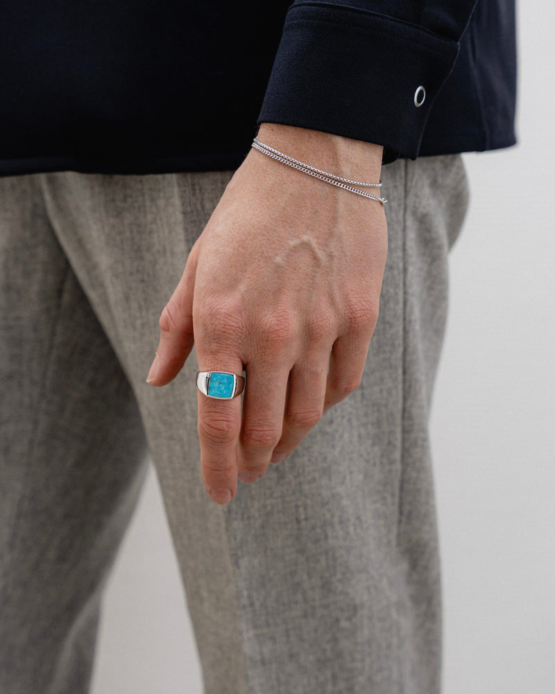 Ein Mann traegt einen Siegelring mit Tuerkis Stein und zwei Silberketten aus 925 Sterling das Zusammenspiel aus Farbe und Glanz wirkt modern und edel Sprezzi Fashion