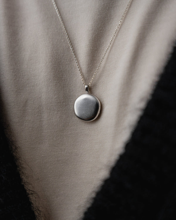 Mann traegt die silberne Medaillon Halskette mit schlichtem Stil die Kombination aus Design und Eleganz betont Selbstbewusstsein Sprezzi Fashion