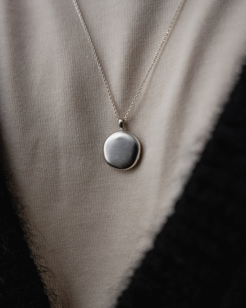 Mann traegt die silberne Medaillon Halskette mit schlichtem Stil die Kombination aus Design und Eleganz betont Selbstbewusstsein Sprezzi Fashion