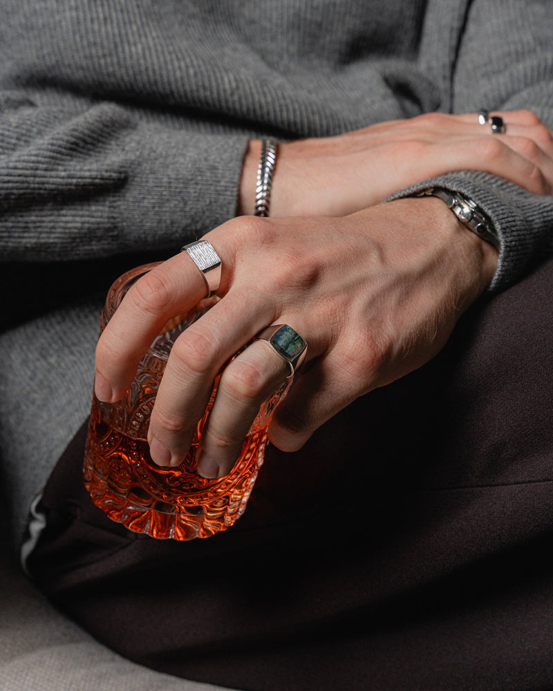 Model traegt den Ring Raw mit gravierter Struktur und den Larvikit Ring mit schimmerndem Stein beide Ringe zeigen praezise Handwerkskunst Sprezzi Fashion