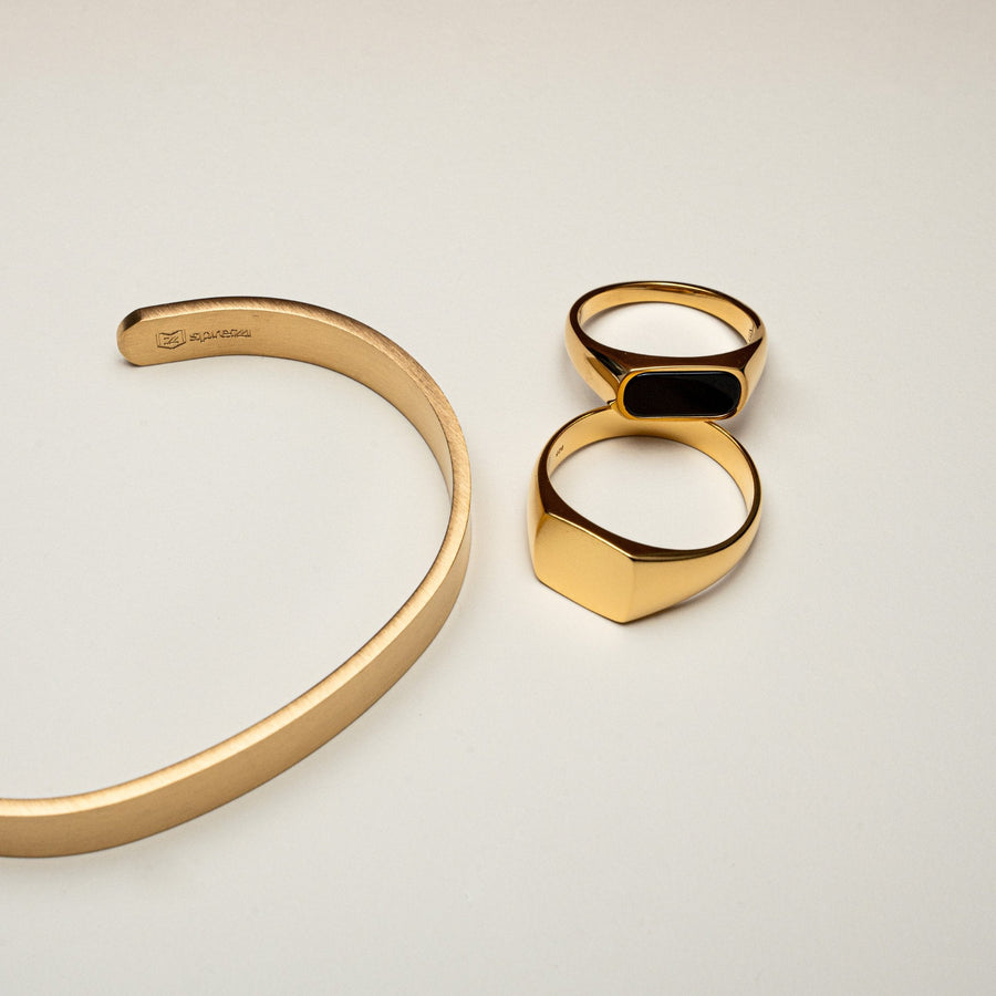 Nahaufnahme zeigt den Kontrast zwischen glaenzendem schwarzem Onyx und matter Goldstruktur beide Ringe aus 18k vergoldetem 925 Silber gefertigt Sprezzi Fashion