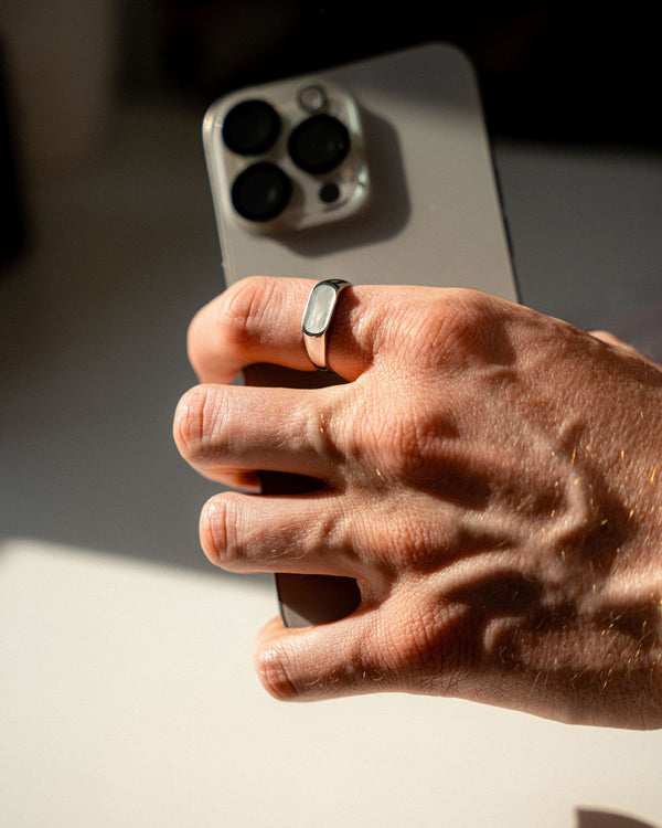 Eleganter Herren Siegelring aus poliertem 925 Sterling Silber mit rechteckigem Perlmutt Naturstein getragen an einer Männerhand während ein Smartphone gehalten wird zeigt modernen maskulinen Stil Sprezzi Fashion