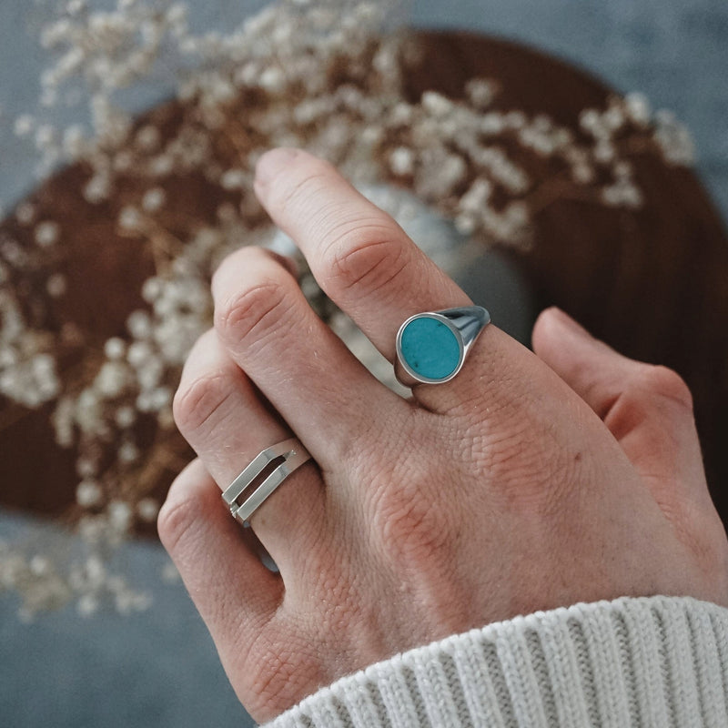 Der getragene Tuerkis Ovalring mit seinem blauen Naturstein zeigt neben dem schlichten Split Ring aus Silber eine moderne harmonische Kombination die Farbe Struktur und klare Formensprache elegant miteinander verbindet und maennliche Praesenz ausstrahlt Sprezzi Fashion