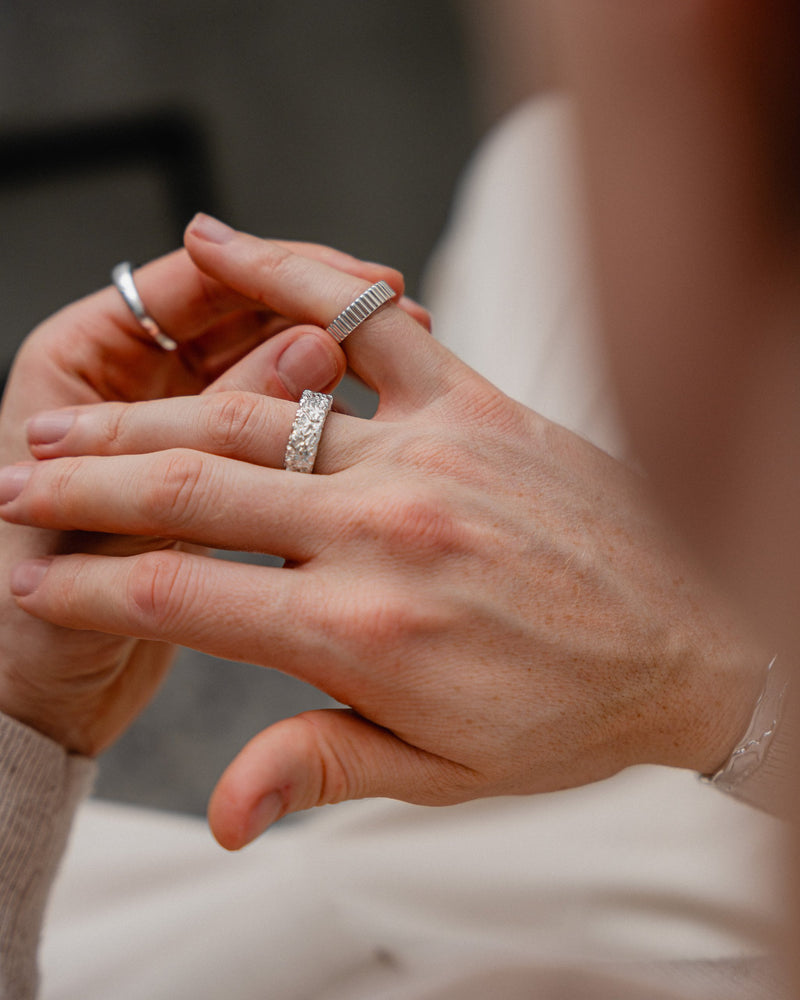 Zwei Silberringe werden parallel getragen und verbinden eine ruhige minimalistische Form mit einer futuristisch rohen Oberflaeche was einen kraftvollen modernen Stil ergibt Sprezzi Fashion