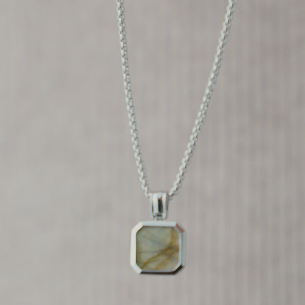 Nahaufnahme einer Herren Halskette aus 925 Sterling Silber mit eckigem Larvikit Stein Anhänger in Grau, dessen natürliche Maserung und feine Farbnuancen durch das Licht dezent hervorgehoben werden Sprezzi Fashion