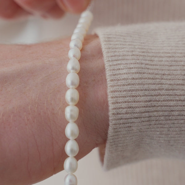 Feines Perlen Armband aus weißen Süßwasserperlen am Handgelenk, deren leicht unregelmäßige Oberfläche einen weichen Glanz und eine elegante Ausstrahlung erzeugt Sprezzi Fashion