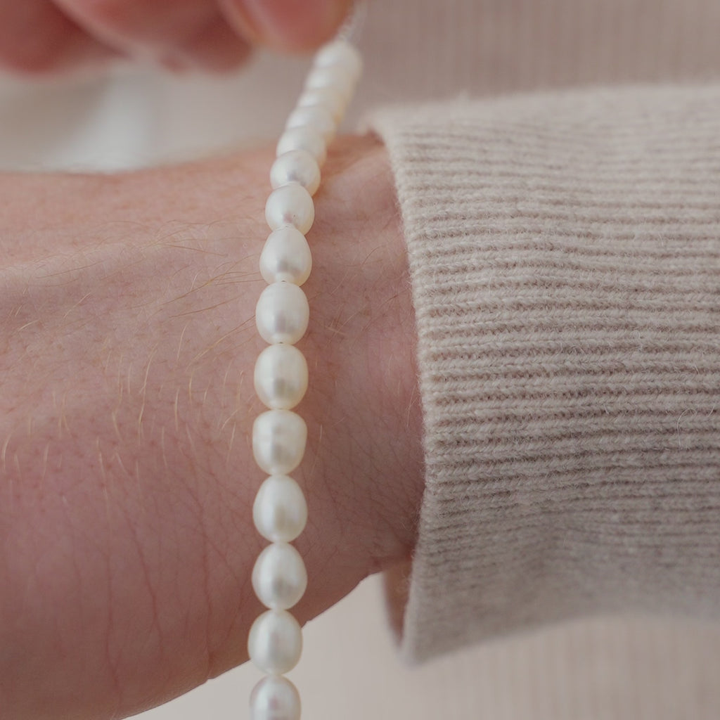 Feines Perlen Armband aus weißen Süßwasserperlen am Handgelenk, deren leicht unregelmäßige Oberfläche einen weichen Glanz und eine elegante Ausstrahlung erzeugt Sprezzi Fashion