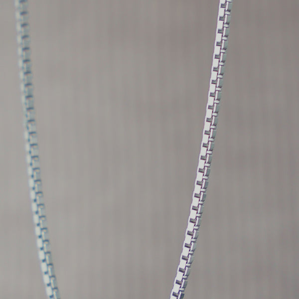 Nahaufnahme einer 925 Sterling Silber Herren Halskette im Box Stil, die leicht gebogen hängt und das Licht gleichmäßig entlang der polierten Glieder reflektiert, wodurch die klare und präzise Struktur sichtbar wird Sprezzi Fashion