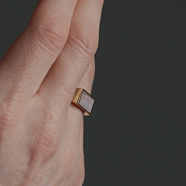 Nahaufnahme eines goldenen Herren Siegelrings mit eckigem blauem Achat Stein, dessen helle Farbnuancen und natürliche Struktur sanft im Licht schimmern Sprezzi Fashion